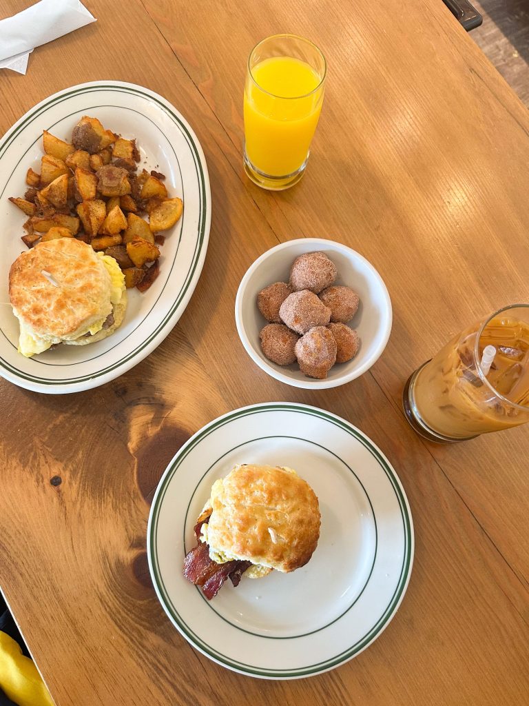 two biscuit sandwiches, cinnamon sugar biscuit bites, crispy potatoes, an iced coffee & a glass of orange juice
